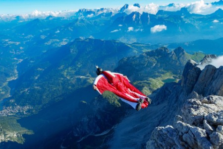 Male wingsuit base jumper taking off from cliff edge