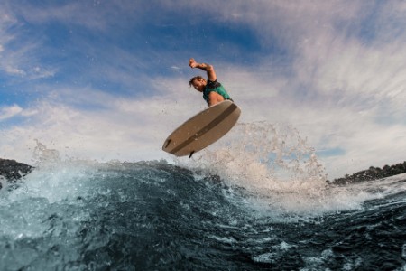 Homem voando no ar em wakesurf sobre onda espirrando