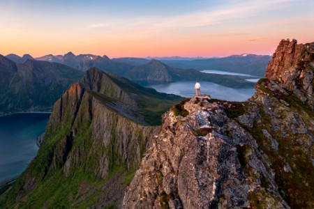 Persona observando el amanecer desde la cima de la montaña noruega