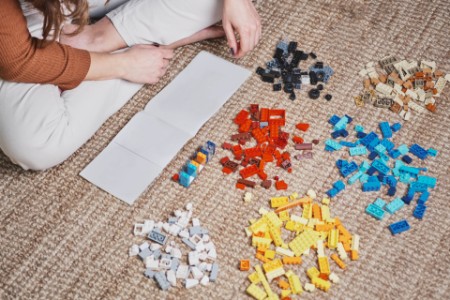 Woman sat on carpet playing with lego bricks