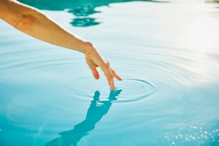 Womans hand touching surface of water
