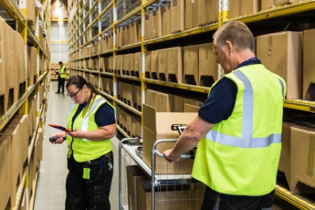 Coworkers working aisle amidst racks distribution warehouse