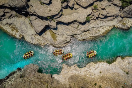 Four yellow rafts floating between rocks down a river