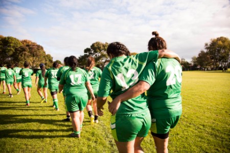 Line of female rugby players walking away helping an injured player