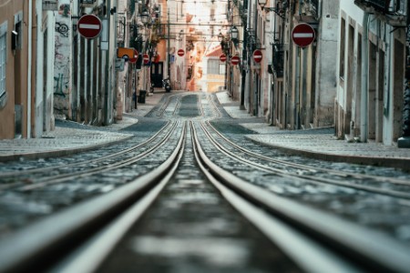 Low angle view of a narrow street with the leading train rails