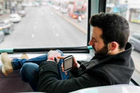 Man in a double decker bus using his smartwatch london uk