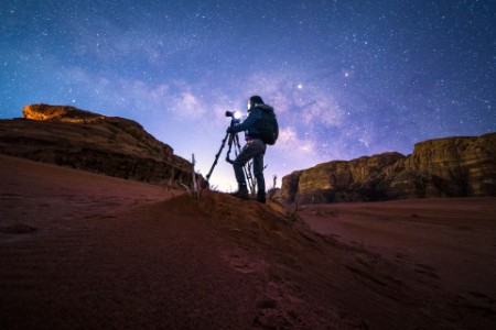 Photographer in wadirum desert under the milky-way