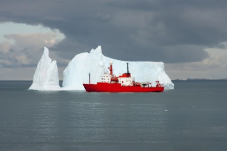Scientific ship passing an iceberg