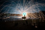 Silhouette of a person spinning wire wool against a night sky