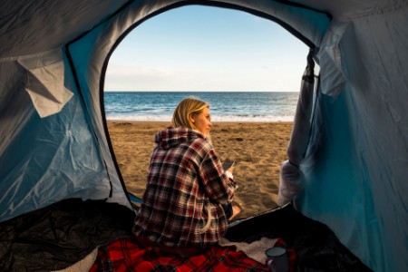 Woman sitting in her tent on the beach