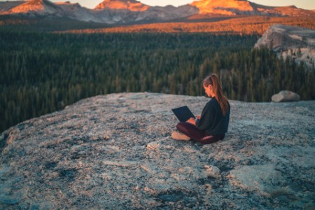 Young woman uses laptop computer on rock slab