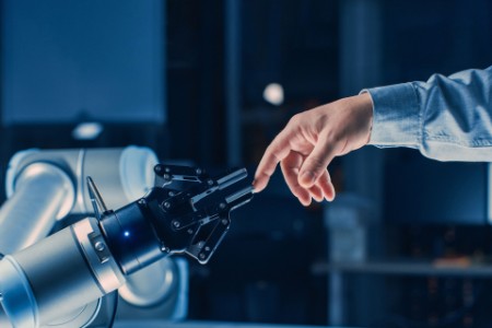 Futuristic robot arm touches human hand