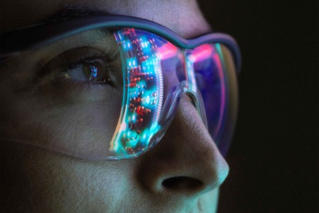 Close-up view of woman in safety glasses with lights reflected in glasses