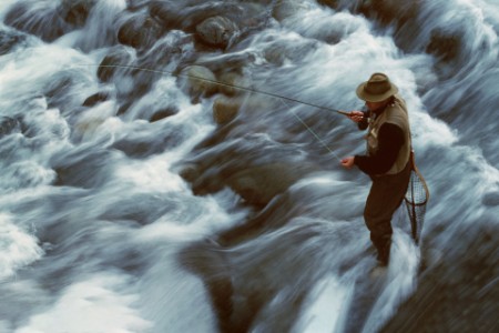 A man stands in a flowing river while fly fishing in Chile