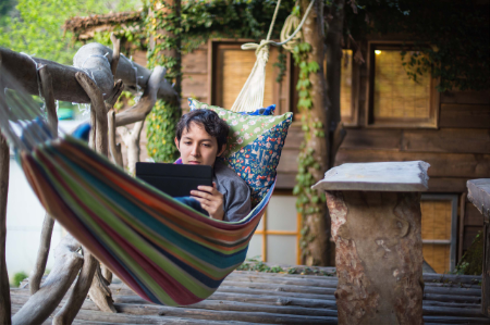 man with digital tablet laying in a hammock