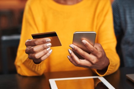 Mujer en un café comprando online con tarjeta de crédito