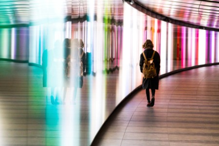 Nainen kävelee futuristisessa valaistussa tunnelissa