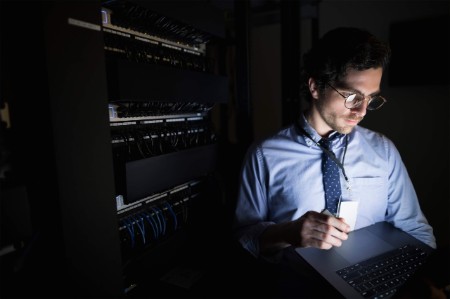 man checking tablet dark server room
