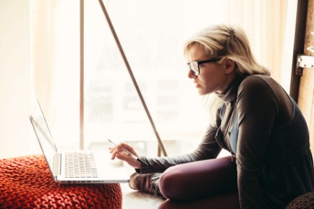 Mujer de negocios con anteojos usando su laptop en la oficina