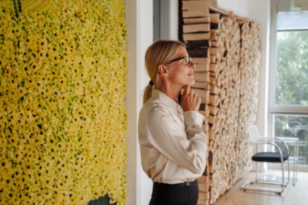 Business woman in office at wall with sunflowers
