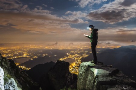Hiker on top of mountain checking mobile device