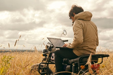 Man using laptop motorcycle rural field