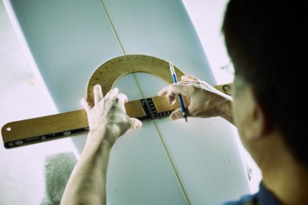 Surfboard shaper measuring board distance in Workshop in Japan