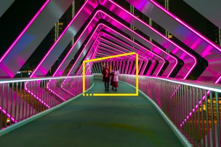 two people walk along a pink pedestrian bridge at Chuanggu Road