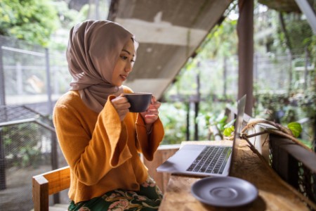 women using laptop outdoors with coffee