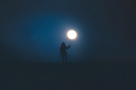 Pequeña niña que sostiene la ilusión óptica de la luna