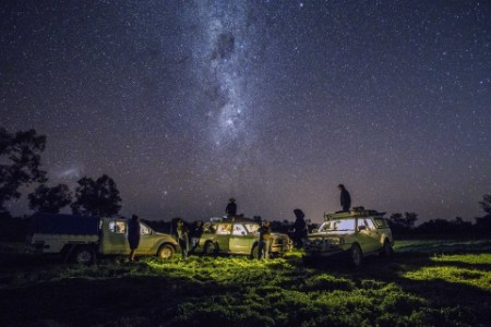 Group of men with four wheel drive vehicles looking at stars in the outback