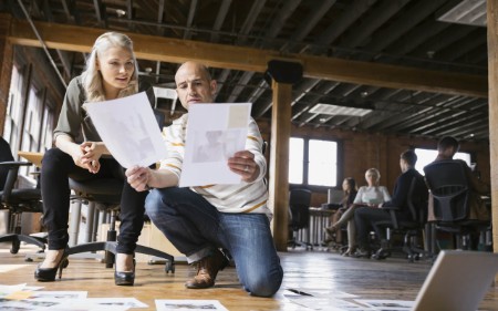 Um homem e uma mulher a analisar documentos no chão do escritório
