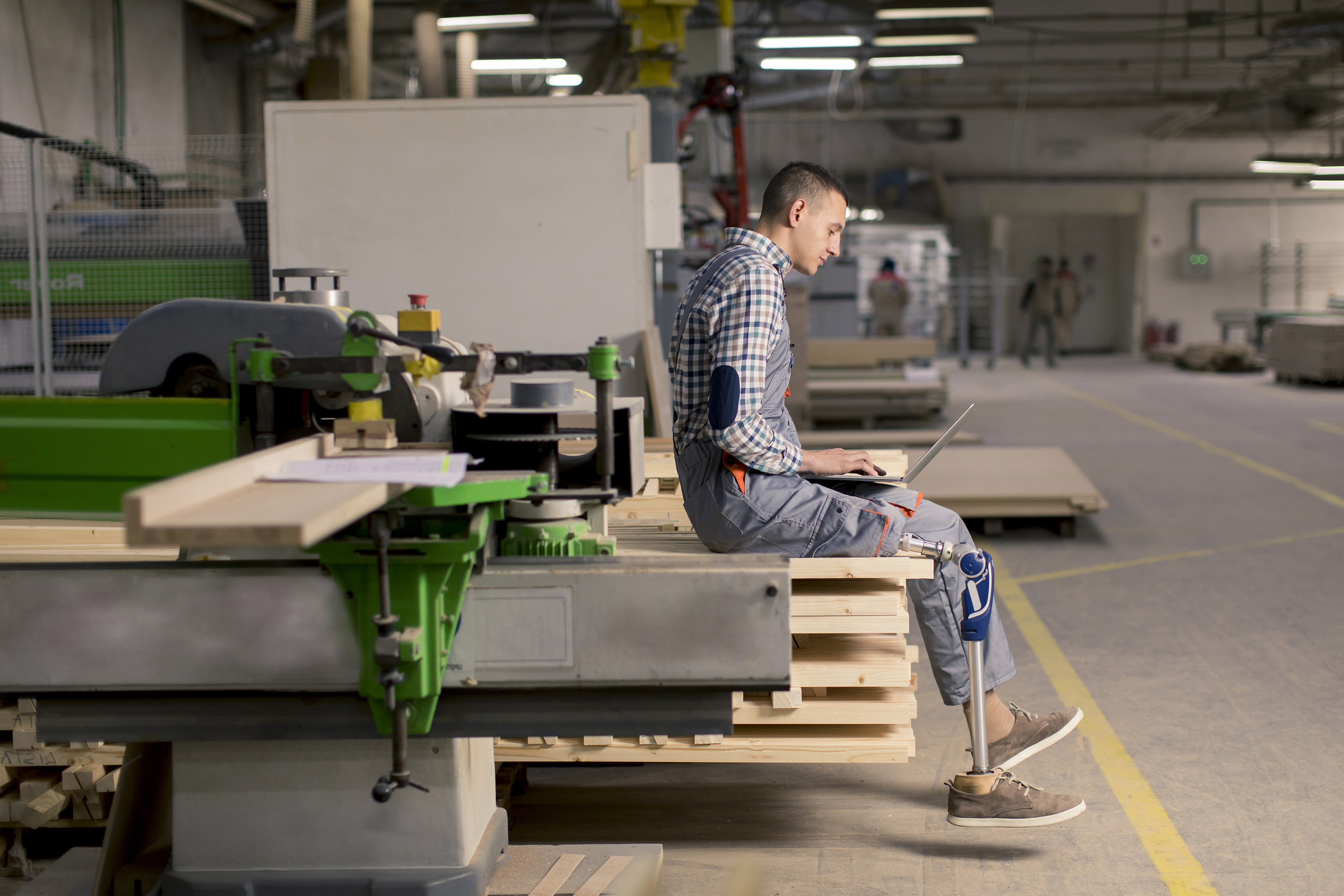 Young man with an artificial leg is working at the factory