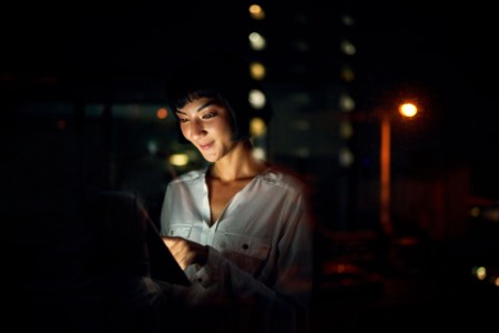Young woman using a digital tablet outside in the city at night