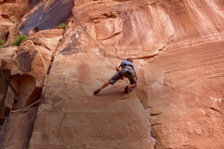 Man climbing a rock wall near moab