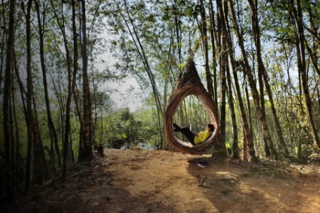 Woman is using laptop inside a bamboo nest by lake