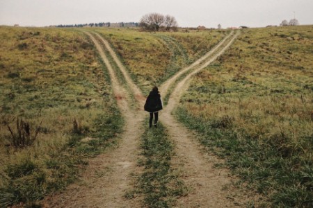 Woman standing crossroads field