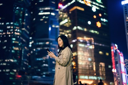 Businesswoman using smartphone against cityscape