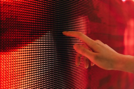 Close up of woman's hand touching illuminated LED display screen