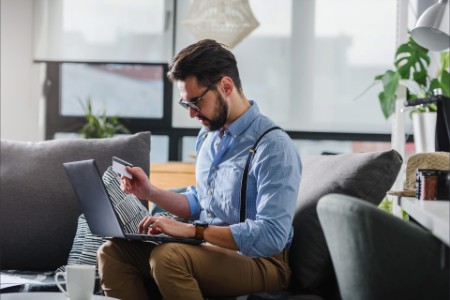 Young bearded man paying with credit card on laptop