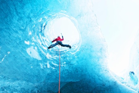 Woman climbing out of glacier cave