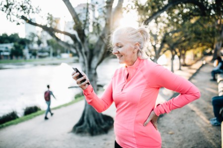Senior female runner browses smart phone