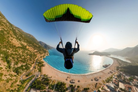 Golden moment of a paraglider pilot flying over the sea