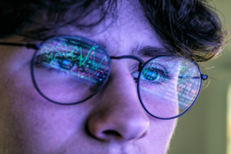 Teenage boy with graph reflection on eyeglasses