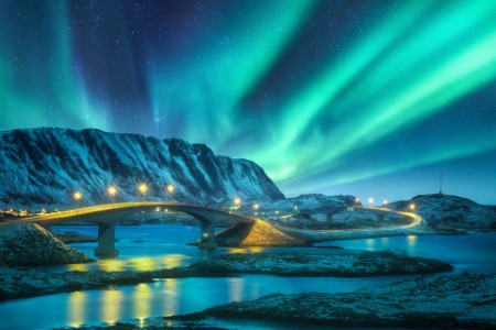 Lofoten Islands, Norway: Bridge, Northern Lights, Snowy Mountains, and Aurora Borealis Reflection in Water.