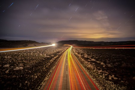 Image of a highway during the evening or night with lightning along the road