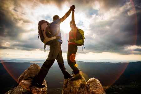 Two people holding hands on top of mountain