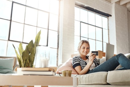 Woman relaxing on the sofa and using a credit card with a laptop static