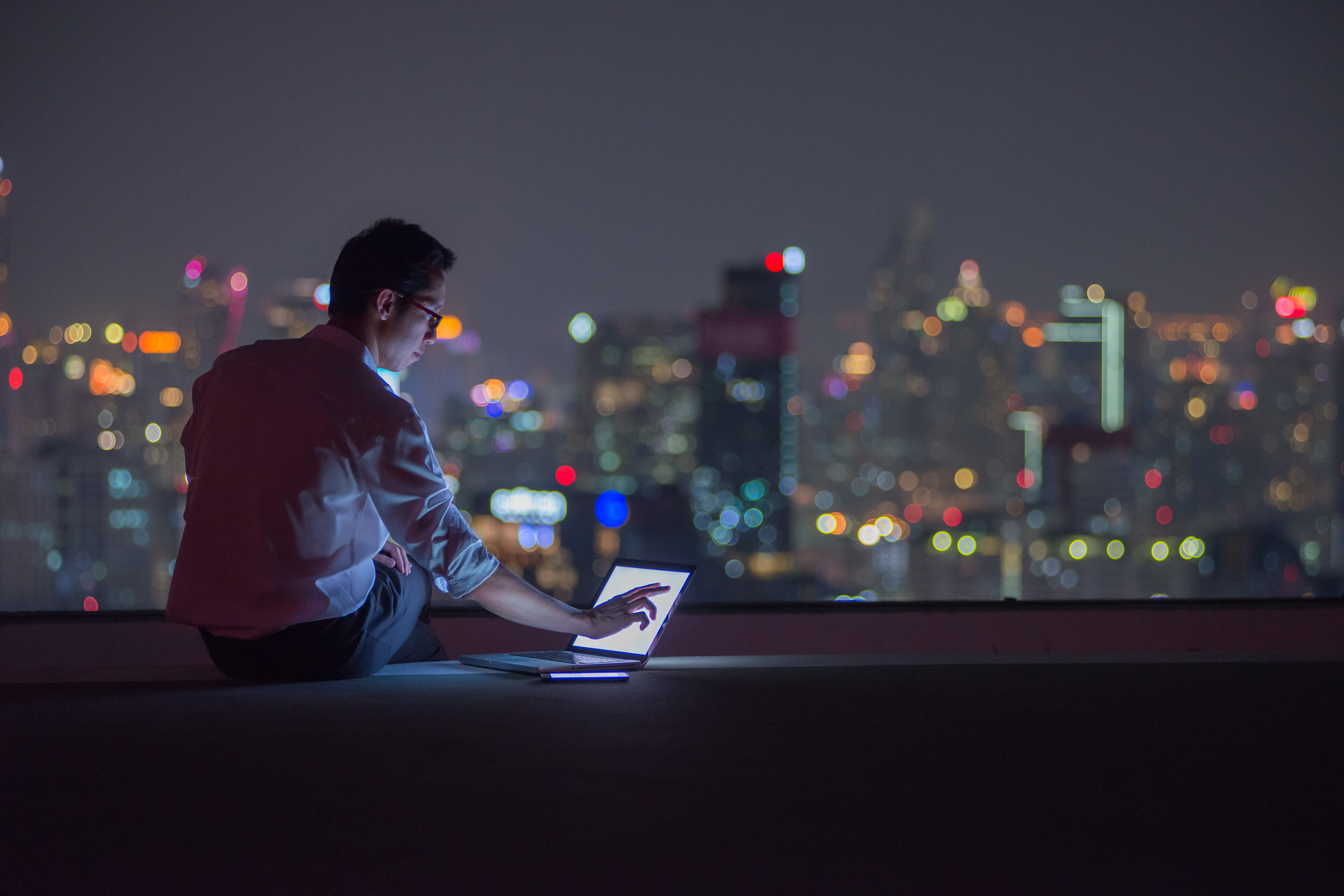 Business man working late on rooftop 