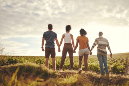 People holding hands in field while looking up at the sky